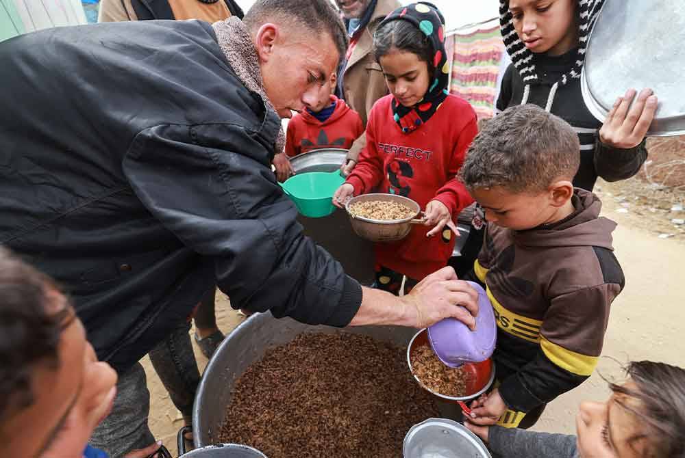 Kumpulan kanak-kanak Palestin mengambil makanan disediakan badan amal selepas krisis kelaparan semakin meruncing di Gaza.
