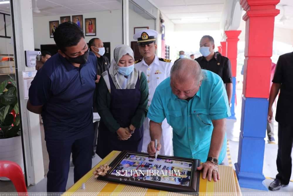 Norfaezah (dua dari kiri) menyaksikan Sultan Ibrahim menandatangani bingkai gambar ketika berkunjung ke R&R Dusun Panti. Foto FB Sultan Ibrahim Iskandar 