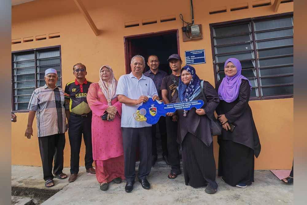 Mohd Zamri menyerahkan replika kunci rumah kepada Yusnita sambil diperhatikan Suhaimi (empat dari kanan).