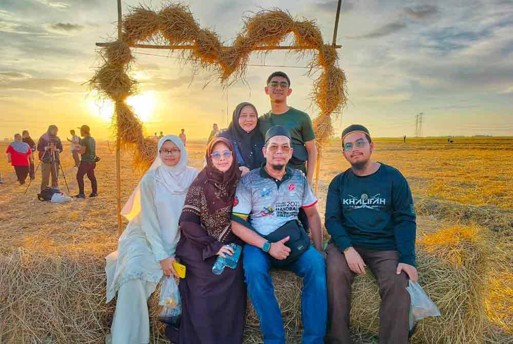 Zulkarnaen (dua dari kanan) bergambar bersama keluarganya berlatarbelakangkan sebuah arca jerami di Kampung Benua.