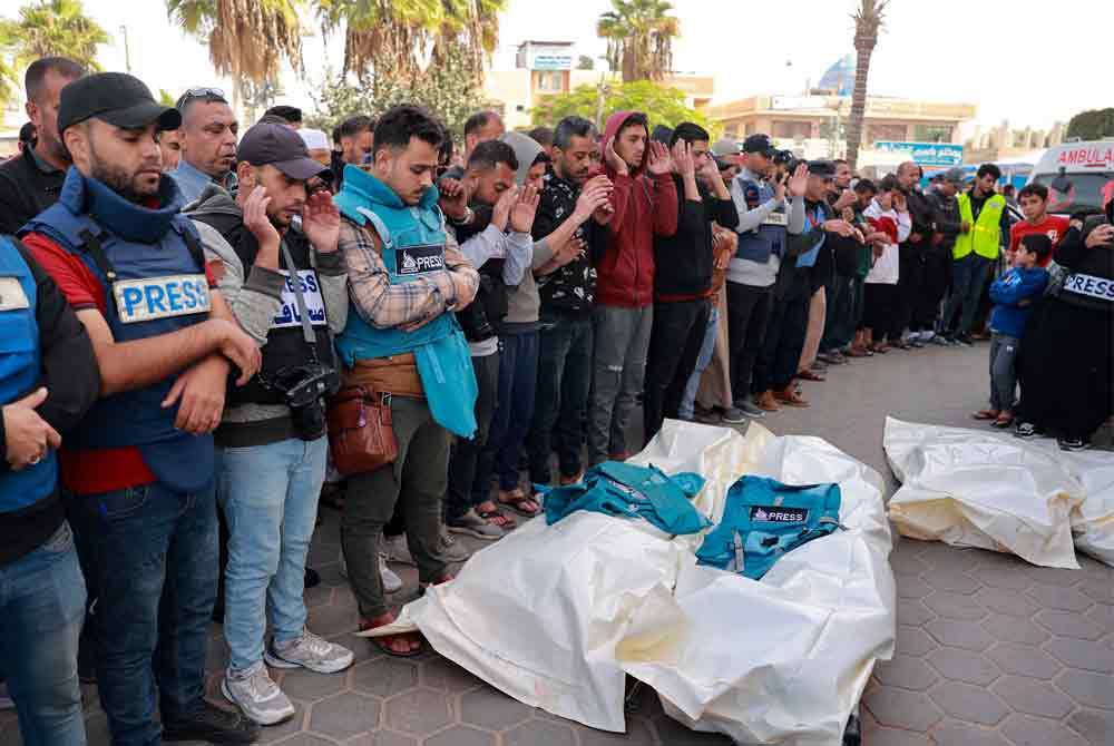 Saudara mara dan rakan menunaikan solat jenazah terhadap dua wartawan Hasouna Slim dan Sari Mansoor yang terbunuh semasa serangan udara Israel di Genting Gaza. - AFP