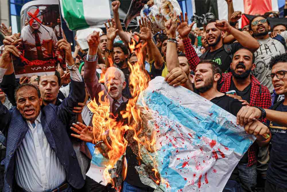 Rakyat Mesir membakar bendera Israel semasa melakukan protes di luar bangunan media di Kaherah. - AFP