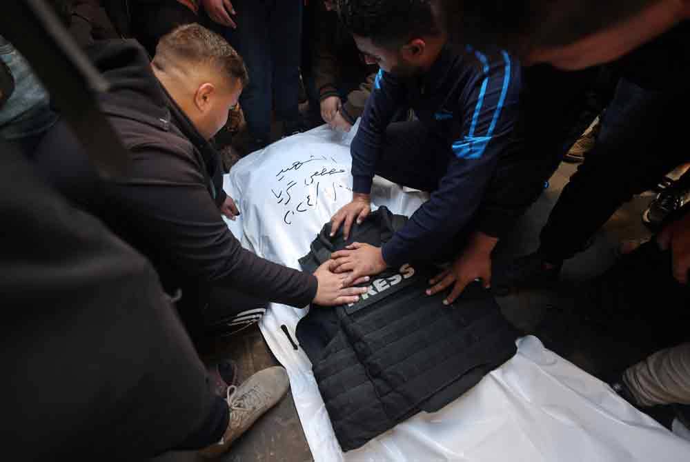 Rakan wartawan mengelilingi jenazah Mustafa Thuria, seorang jurugambar bebas agensi AFP yang terbunuh semasa serangan Israel di Rafah. - AFP