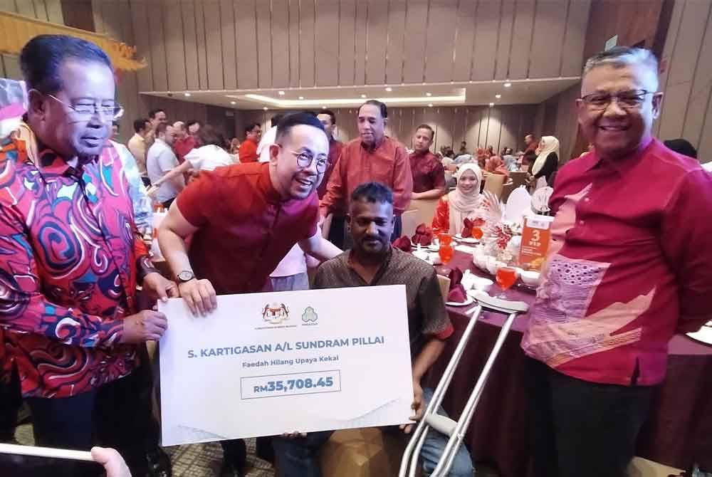 Steven Sim menyampaikan sumbangan kepada salah seorang penerima.