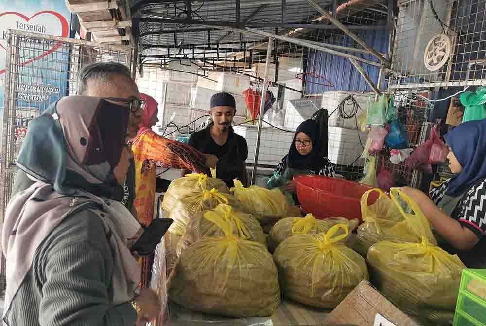 Ahmad Bukhari (tiga dari kanan) melayan pelanggan yang berkunjung di premisnya yang beroperasi berdekatan Muzium Negeri Terengganu di Losong, Kuala Terengganu.
