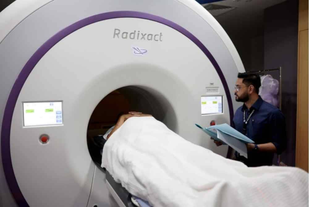 Pakar Onkologi Klinikal, Dr Eznal Iswadi Mohd Mahidin (kanan) merawat pesakit kanser melalui mesin tomoterapi di HKL baru-baru ini.