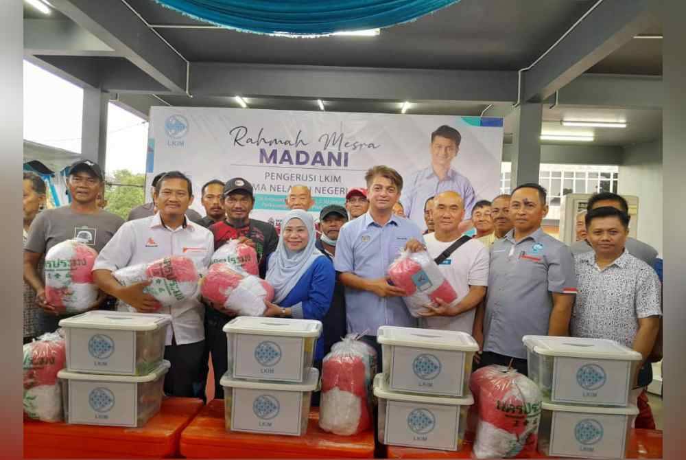 Muhammad Faiz (empat dari kanan) menyampaikan bantuan peralatan penangkapan ikan kepada nelayan di Pejabat LKIM Pontian pada Ahad.