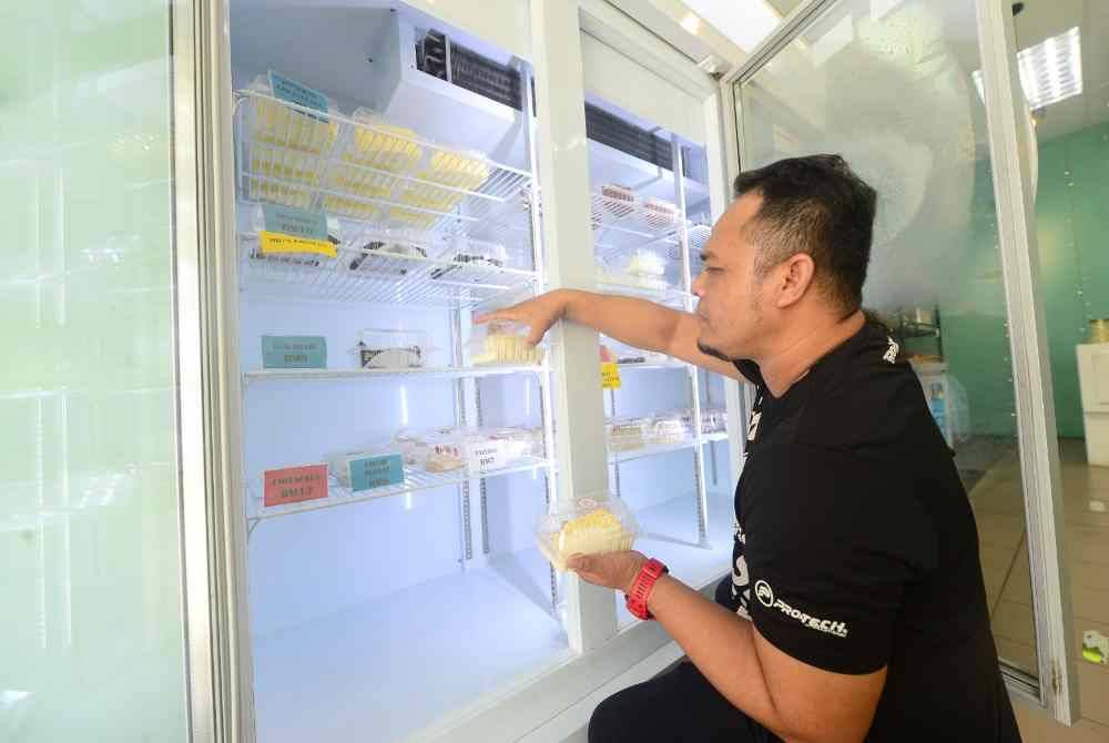 Mohamad Rezal membantu menyusun pelbagai jenis kek yang dijual.