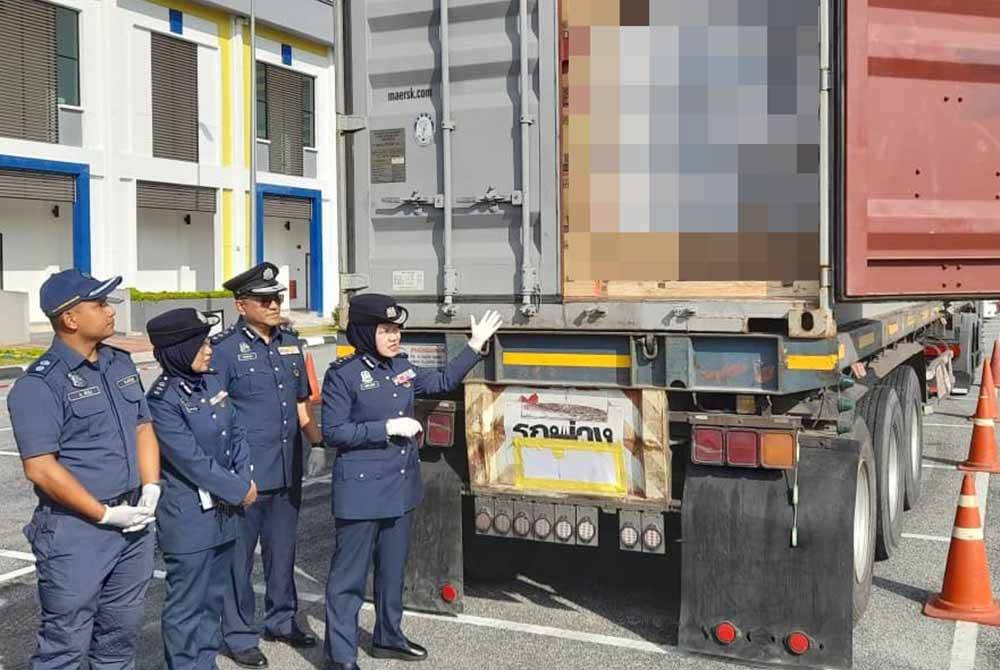 Nor Izah (kanan) menunjukkan botol air zam zam yang disembunyikan bersama pelembut pakaian dalam sebuah kontena.