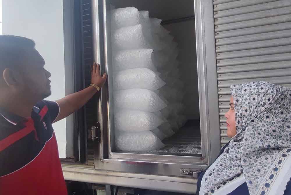 Ahmad Yusop dan Suzana (kanan) melihat bekalan ais kuib telah disusun dalam lori ais.