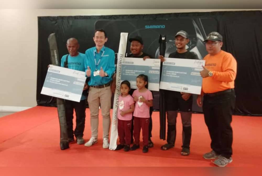 Kelvin (dua dari kiri) menyampaikan hadiah kepada pemenang utama Cuti-Cuti Malaysia Shimano Surfcasting di MITC, Melaka.