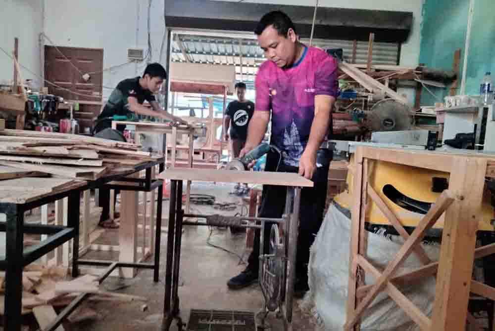 Zaharin menunjukkan kaki mesin jahit yang diubah suai sebagai meja.