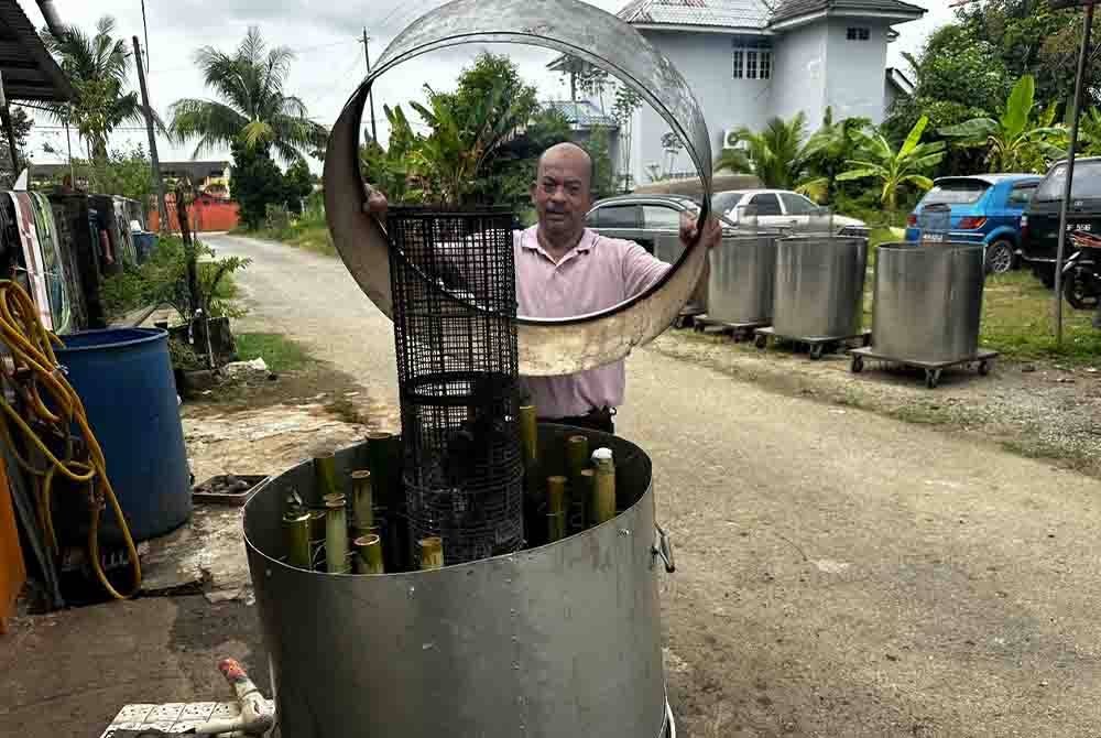 Fauzi mengangkat penutup keluli di bahagian atas mesin.