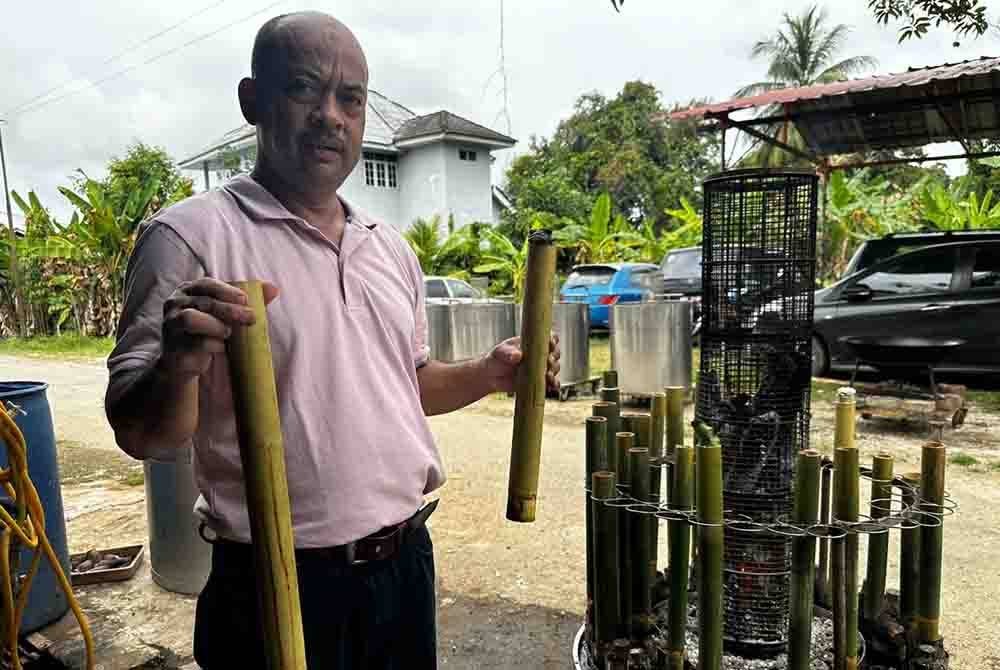 Fauzi mengambil lemang yang siap dimasak menggunakan mesin ciptaannya.