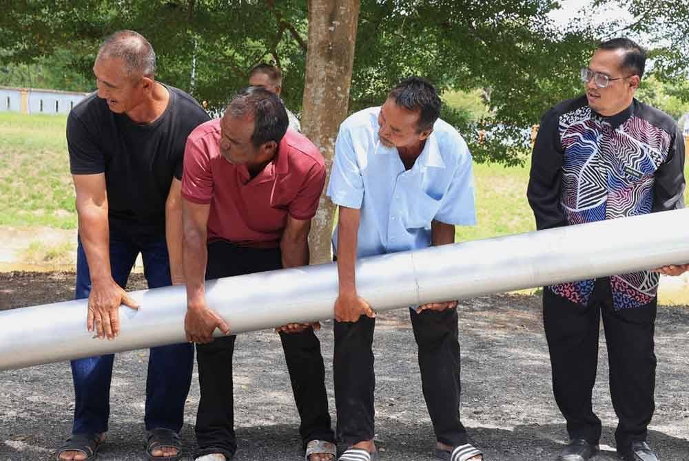 Mohd Faizul (kanan) turut sama mengangkat salah satu peralatan pam backward.