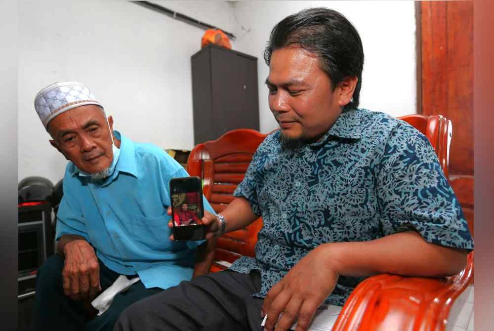 
Mohd Asna (kanan) menunjukkan gambar Allahyarham sambil diperhatikan Samad