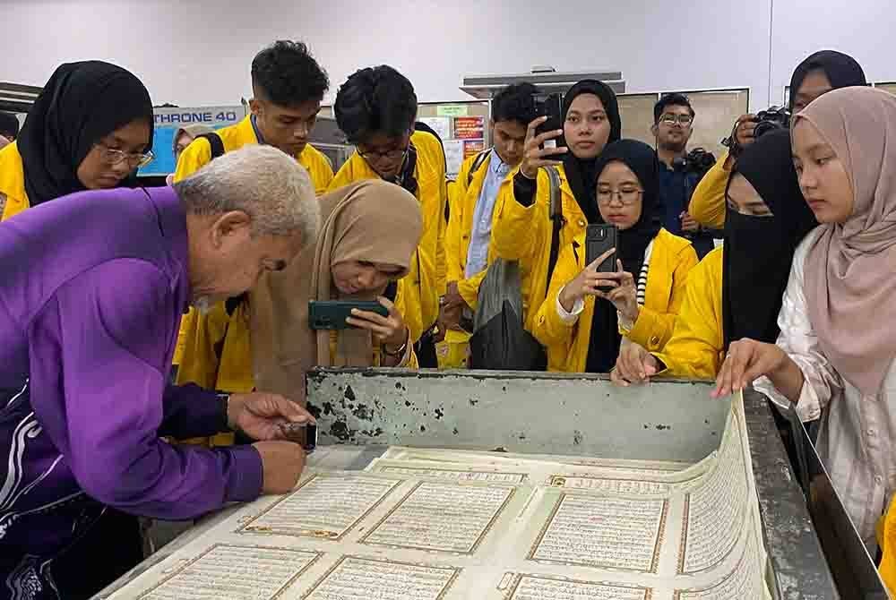 Hashim (kiri) menunjukkan proses semakan kualiti cetakan al-Quran kepada pelajar UPI.