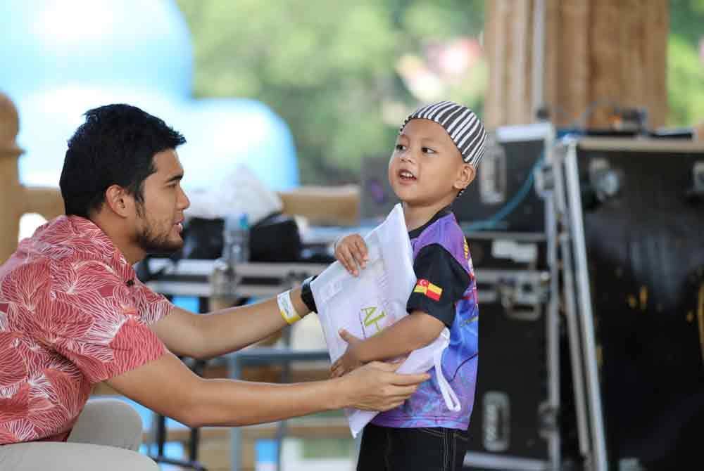 Muhammad Zikri menyampaikan kelengkapan persekolahan kepada penguni Rumah Amal Al-Firdaus ketika program 'Waves of Joy' di taman tema Sunway Lagoon, Petaling Jaya pada Khamis.
