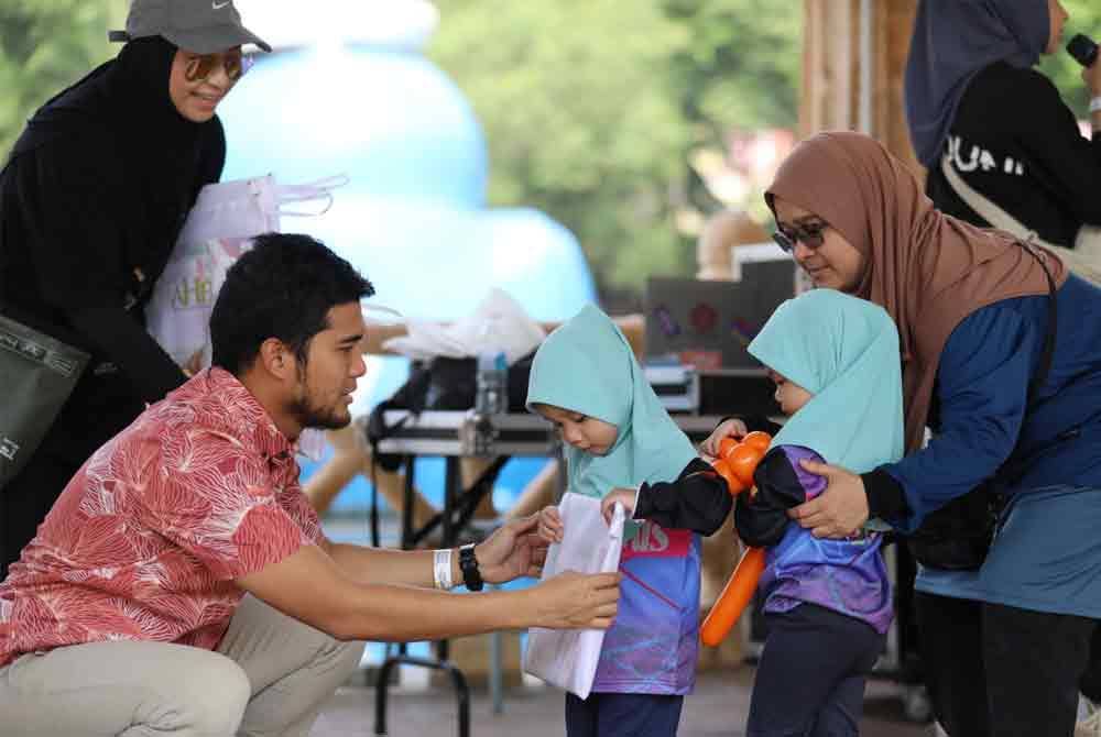 Muhammad Zikri menyampaikan kelengkapan persekolahan kepada penguni Rumah Amal Al-Firdaus ketika program 'Waves of Joy' di taman tema Sunway Lagoon, Petaling Jaya pada Khamis.