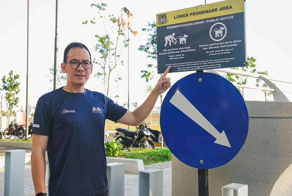 Joshua menunjukkan papan tanda mengenai syarat membawa haiwan peliharaan di Taman Gurney Bay.