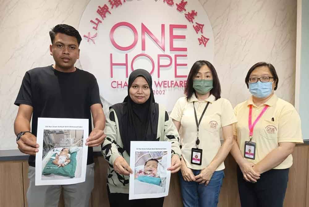 Mohd Sobri (kiri) dan isterinya, Siti Safila (dua dari kiri) menunjukkan gambar anak mereka ketika mendapatkan bantuan daripada One Hope Charity & Welfare, baru-baru ini.