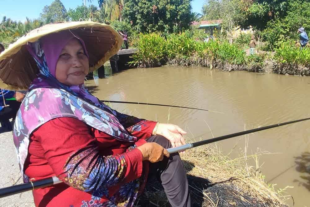 Cuaca panas tidak menghalang Zaharah (kiri) dan Ramami (kanan) memancing ikan di tali air.