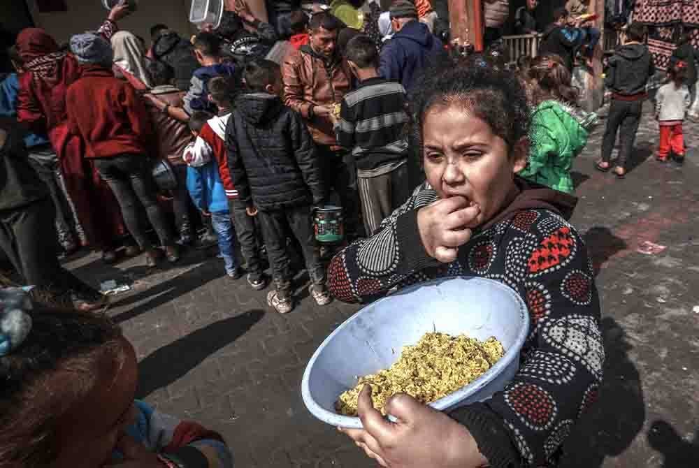 Seorang kanak-kanak perempuan menerima bantuan bekalan makanan di Rafah. - AFP