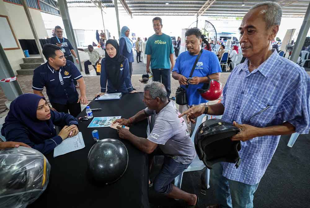 Pengunjung tidak melepaskan peluang mendapatkan topi keledar yang diagihkan secara percuma. Foto Bernama