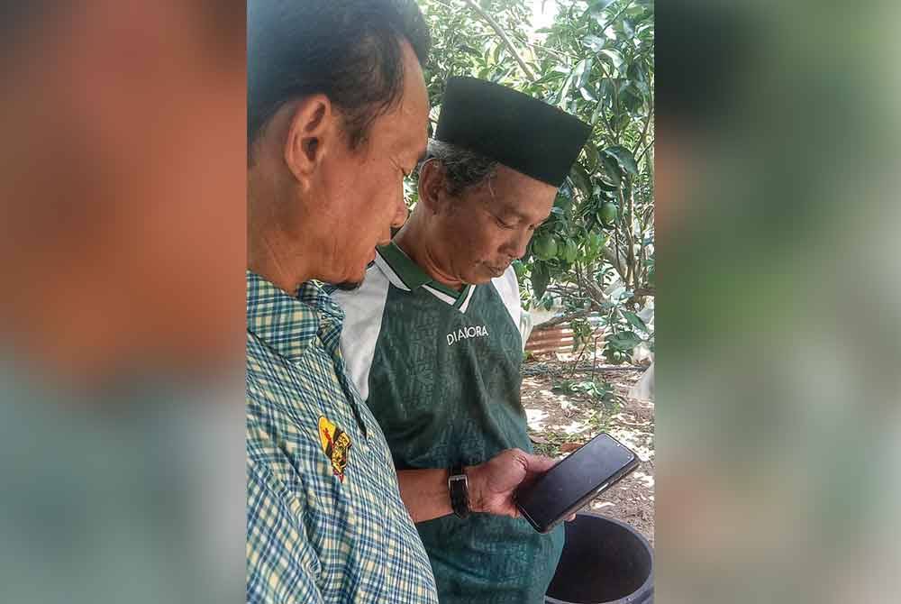 Razman (kanan) ketika menunjukkan gambar Rosidi kepada rakannya.