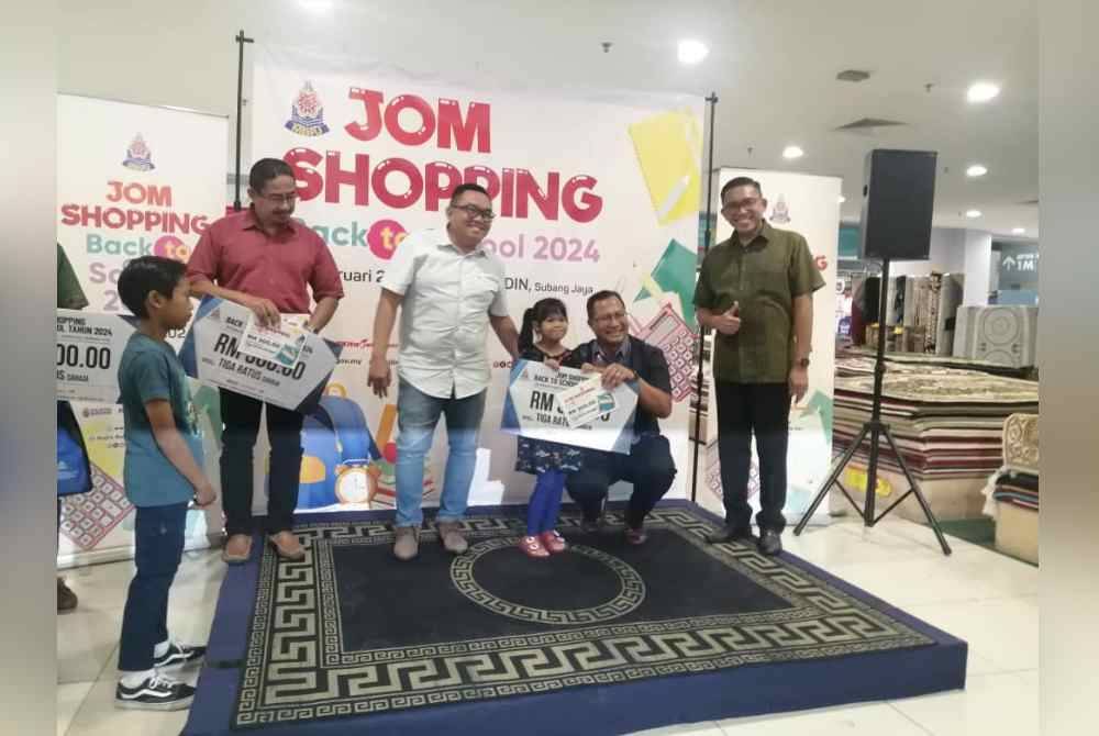 Mohamad Zahri (dua dari kanan) menyampaikan sumbangan baucar Jom Shopping Kembali Ke Sekolah.