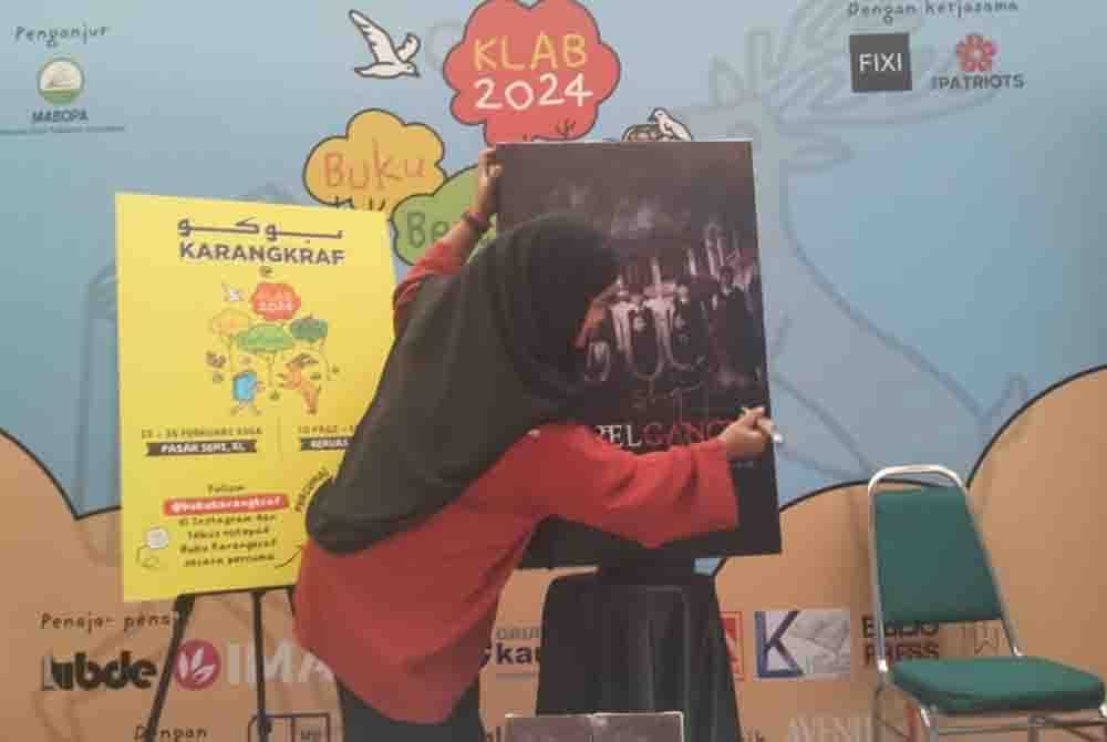 Nurul Syahida menurunkan tandatangan sebagai simbolik pelancaran novel Doppelganger di Pasar Seni, Kuala Lumpur pada Ahad.