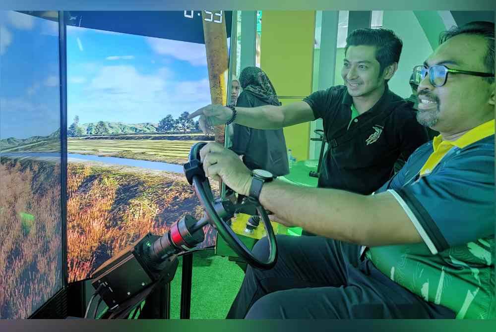Zurihanmi (kanan) mencuba simulasi pemanduan jentuai padi di Pavilion KPKM sempena PMR yang berlangsung di Kompleks Sukan Kuala Selangor.