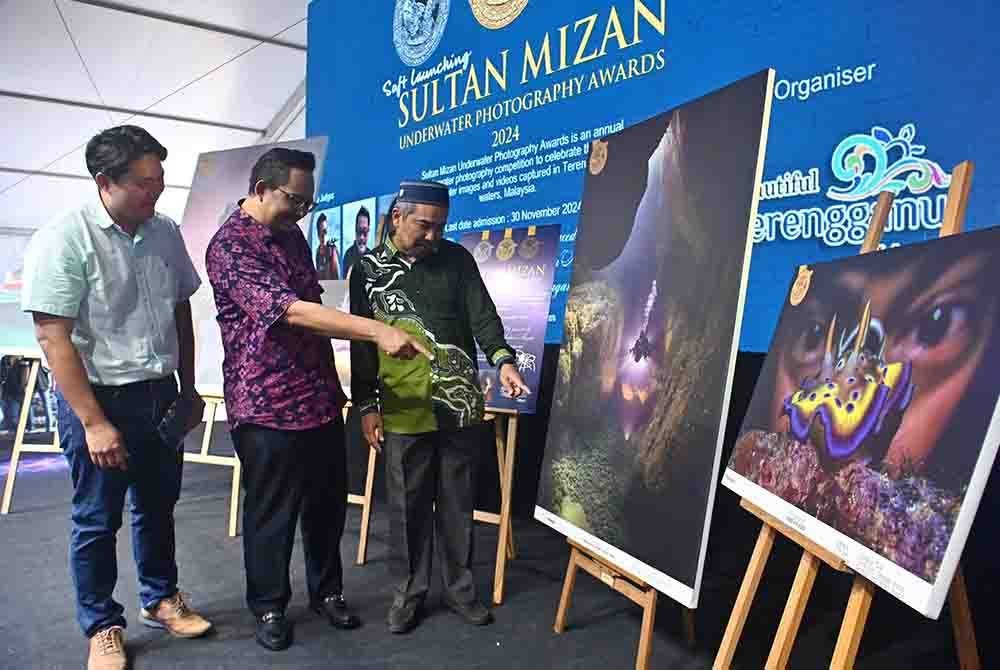 Sulaiman (kanan) bersama Ahmad Ridzwan (tengah) melihat pameran gambar dasar laut sempena majlis pelancaran SMUPA di Dataran Shahbandar, Kuala Terengganu.