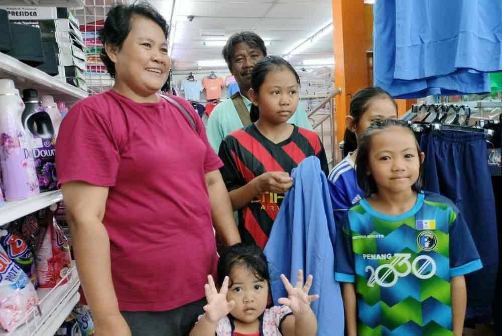 Nora (kiri) bersama keluarganya ketika membeli-belah pakaian sekolah melalui Jualan Rahmah di Pasaraya CY Pekan Rompin.