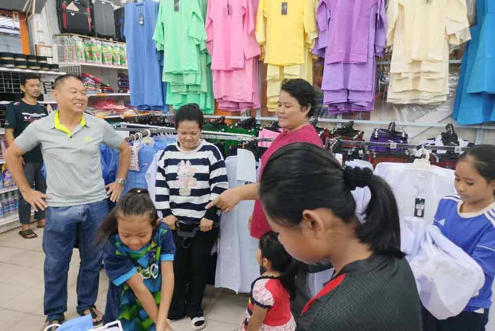 Keu Chai (kiri) berkesempatan berbual dengan Nora (tiga kiri) ketika membeli-belah pakaian sekolah di pasaraya berkenaan.