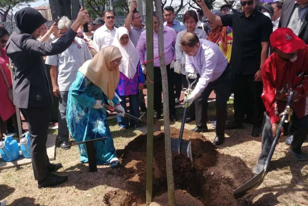 Gimik penanaman pokok oleh Wan Azizah (kiri) bersama Kamarulzaman pada majlis perasmian Taman Kejiranan Ikhlas Bandar Tun Razak pada Selasa.