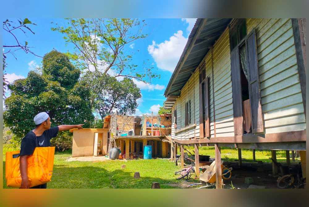 Mohd Aidil menunjukkan rumahnya yang teralih daripada kedudukan asal akibat banjir besar tersebut.