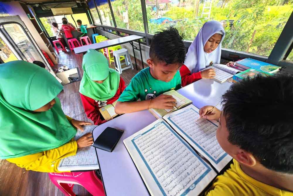 Pelajar pusat pengajian al-Quran di Taman Seri Rembau tekun membaca al-Quran di dalam bas lama yang diubah suai.