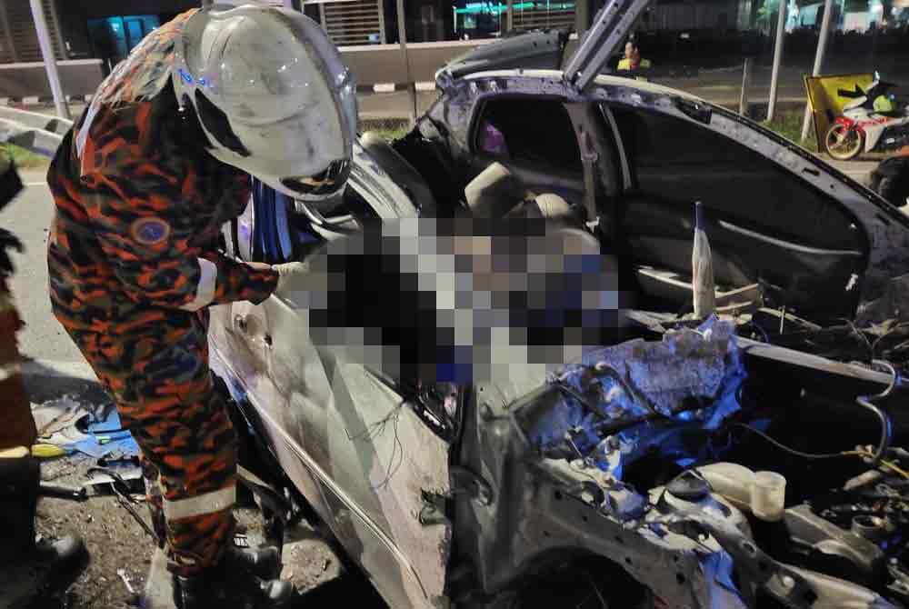 Anggota bomba sedang mengeluarkan mangsa yang tersepit di bahagian tempat duduk pemandu.