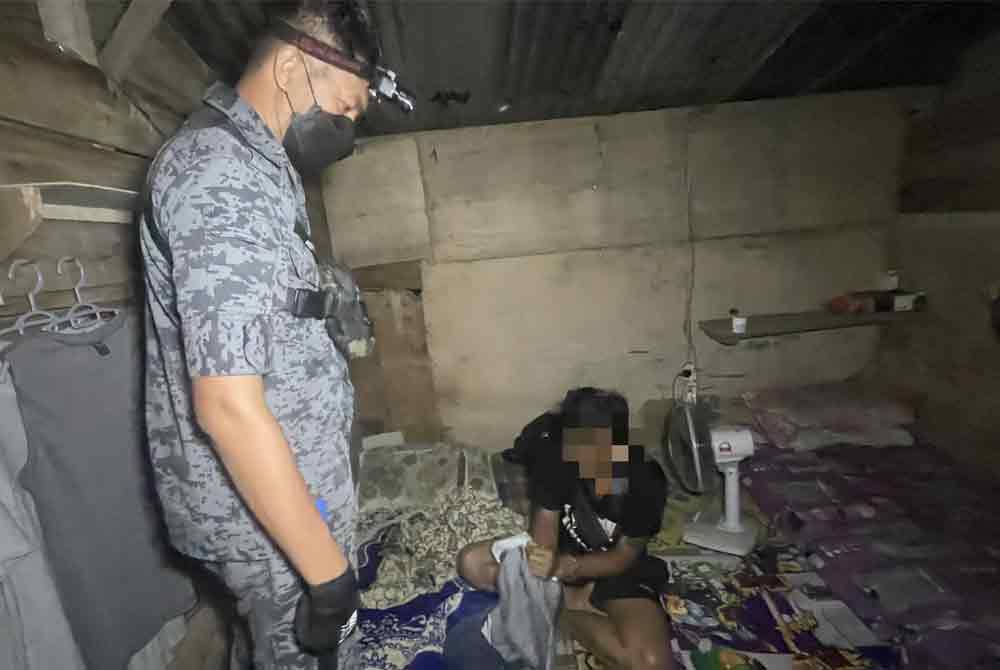 Anggota JIM Pahang melakukan pemeriksaan ke atas salah seorang warga asing dalam serbuan ke atas beberapa rumah kongsi pekerja ladang sawit sekitar Maran pada awal pagi Rabu.