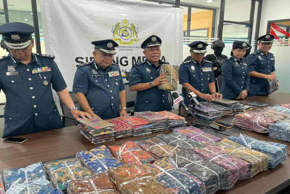 Mohd Nasir (tiga dari kiri) menunjukkan kain sarung yang berjaya dirampas kastam di sebuah gudang di Jalan Kolombong, Kota Kinabalu.