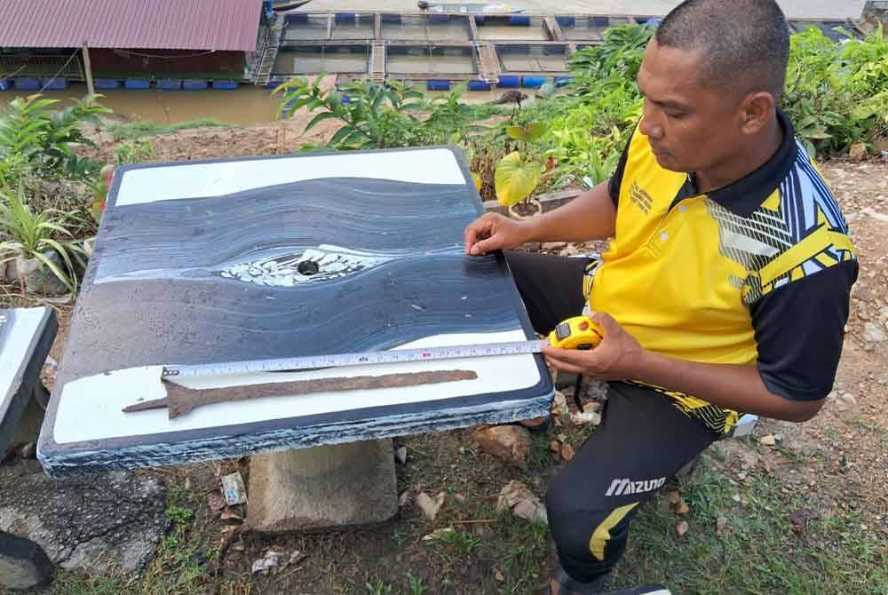 Hamidi mengukur keris panjang yang dijumpai tersangkut pada jaring ketika menjaring ikan di Sungai Pahang Kampung Kelola Pulau Tawar, Jerantut awal Januari lalu.