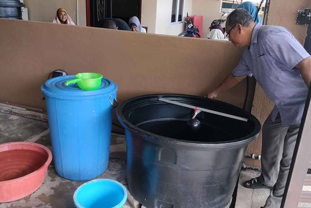 Ahmad Lutfi menunjukkan tangki air di luar rumah bagi menakung air akibat gangguan bekalan yang berlarutan.