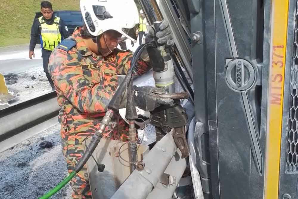 Anggota bomba melakukan kerja-kerja menyelamat mengeluarkan pemandu treler yang tersepit. Foto Bomba Perak