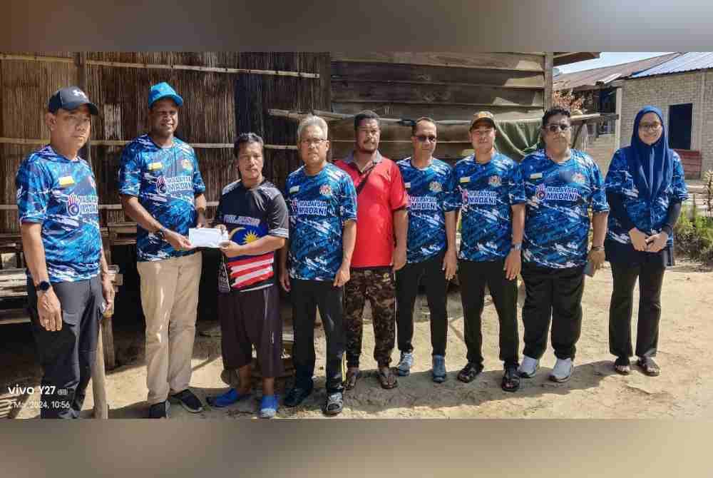 Kesavan (dua dari kiri) menyerahkan bantuan bencana kepada Asmadi di rumahnya di Kampung Kajang, Bawong pada Sabtu.