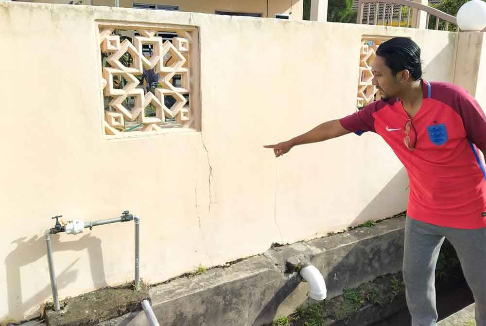 Zulfadzli menunjukkan keadaan struktur di hadapan rumahnya yang retak dipercayai disebabkan gegaran ketika lori melalui jalan berkenaan.
