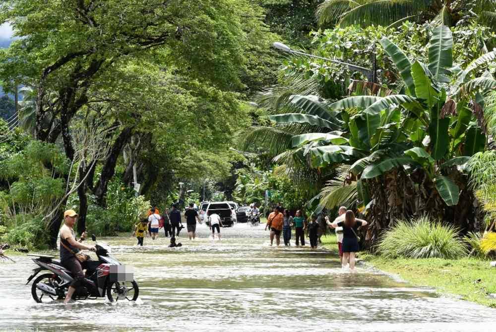 Penduduk Taman Malihah mengharungi banjir untuk berpindah ke pusat pemindahan sementara (PPS) akibat hujan yang turun secara berterusan sejak semalam lagi di kawasan itu ketika tinjauan petang tadi. Foto Bernama