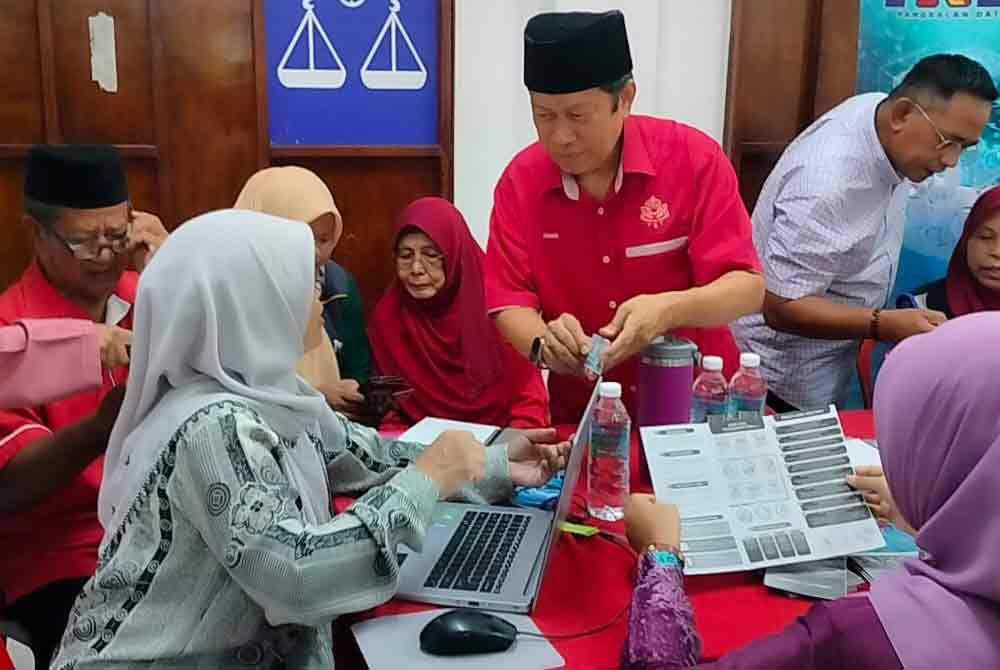 Ahmad (dua dari kanan) membantu ahli UMNO mendaftar PADU di Dewan UMNO Pontian pada Ahad.