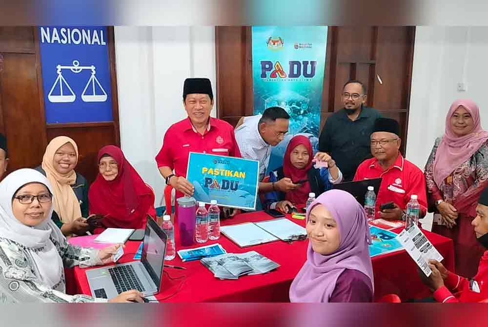Ahmad memegang plakad PADU ketika meninjau proses pendaftaran sistem tersebut di Dewan UMNO Pontian pada Ahad.