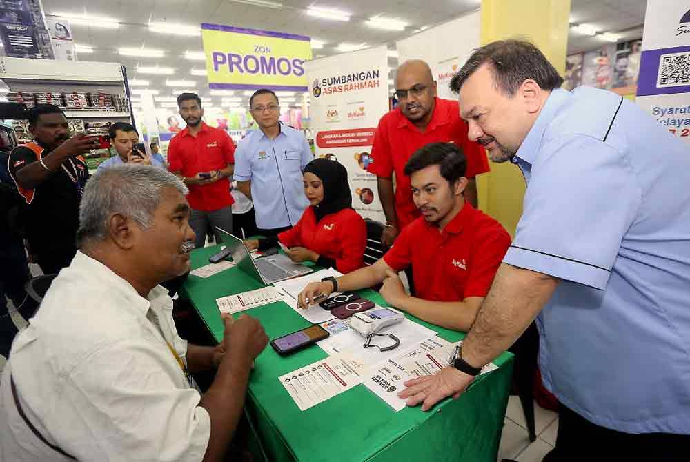 Amir Hamzah (kanan) beramah mesra bersama warga emas yang juga penerima bantuan Program Sumbangan Asas Rahmah (SARA) di kaunter pendaftaran MyKasih di Pasaraya TF Value hari ini. - Foto: Bernama